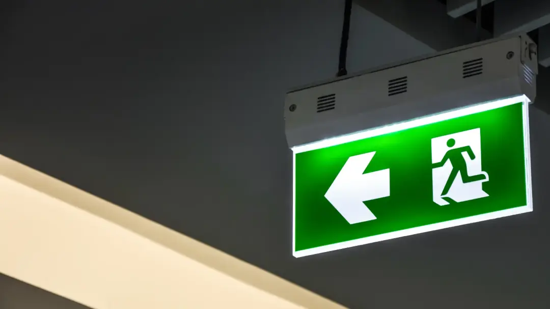 An emergency exit sign above a steel fire door